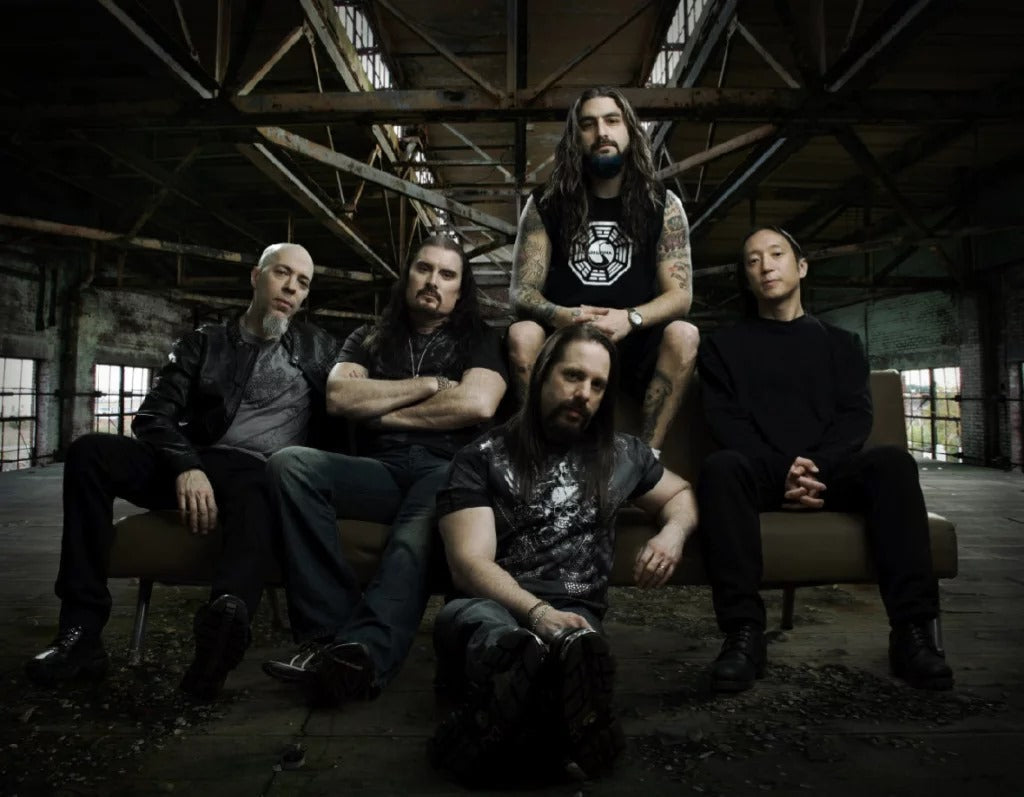 Dream Theater band members sitting in a dark industrial space showcasing Dream Theater t-shirts for sale